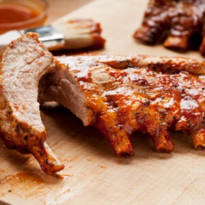 Barbecue ribs with sauce on a cutting board.